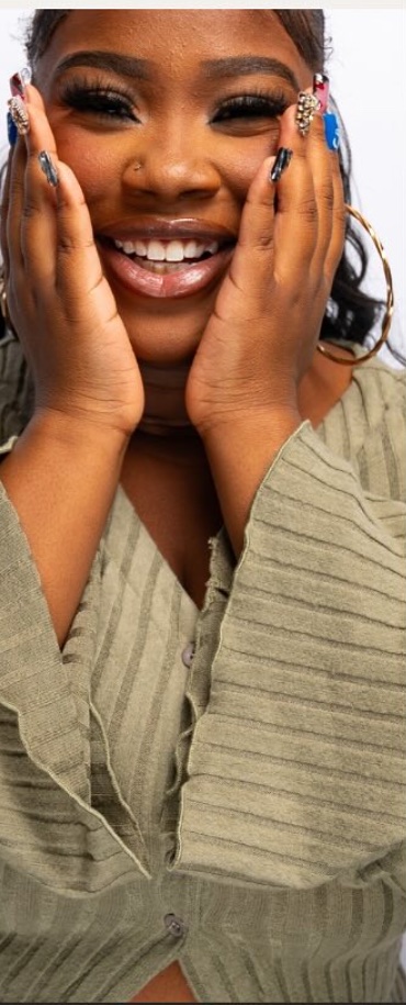 The nail artist behind Pretty Nail Paradise smiling with her hands framing her face, wearing her own custom nail set